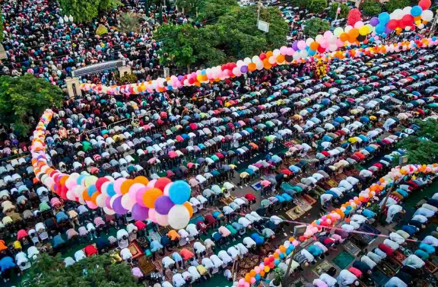 Vista aerea di una grande preghiera all'aperto durante il Festival Egiziani per l'Eid-ul-Fitr, con migliaia di fedeli e archi di palloncini colorati e vivaci.